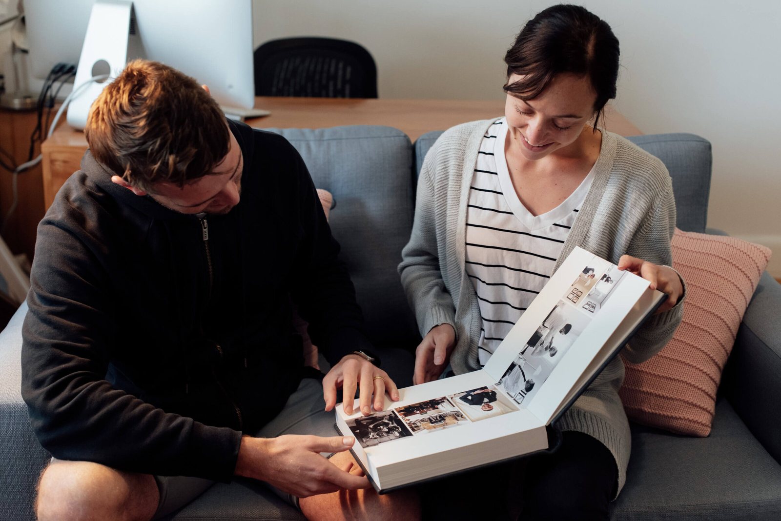 Two people on a sofa turning the pages of a wedding album