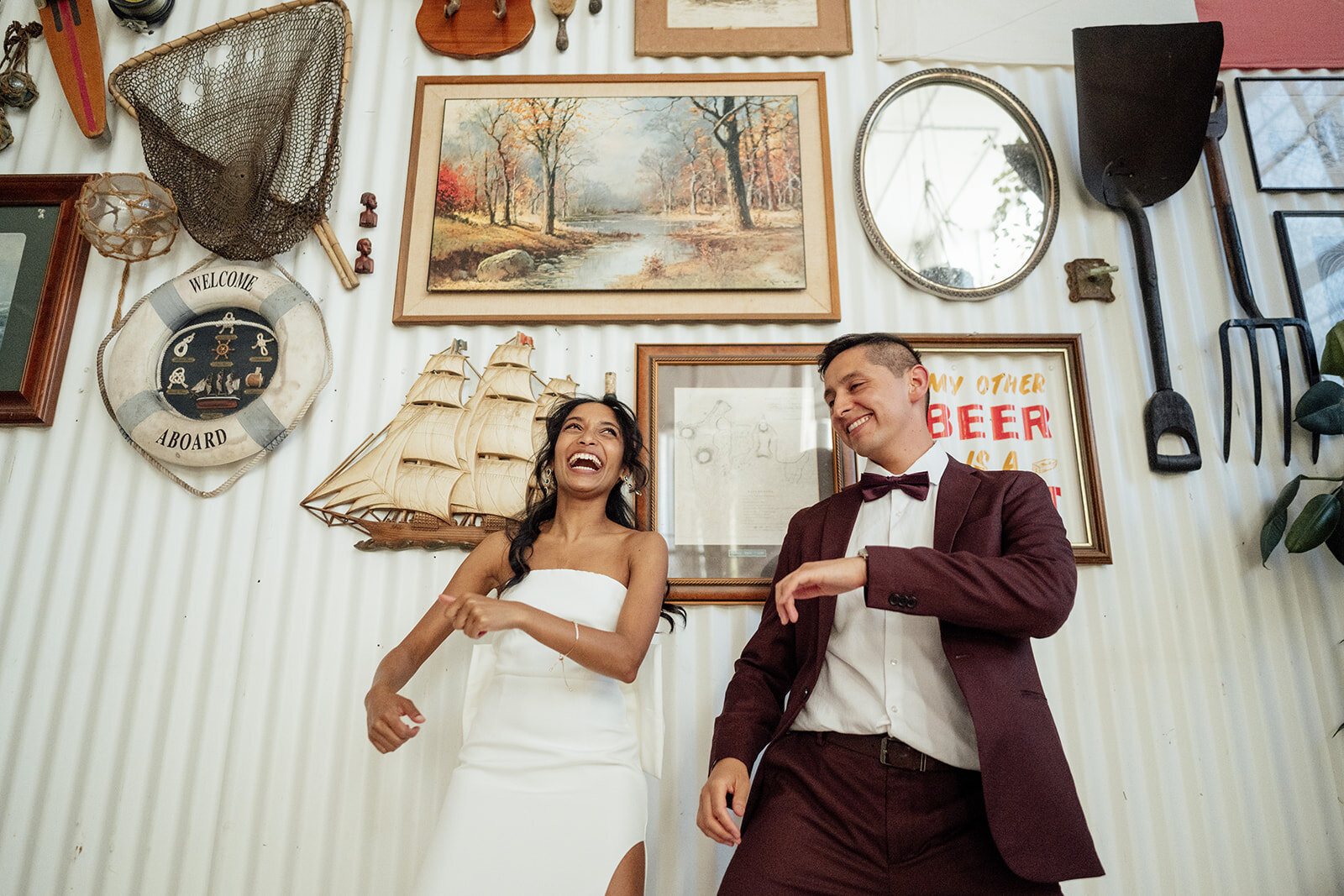 A bride and groom dancing through their reception in a room full of picture frames as guests film them