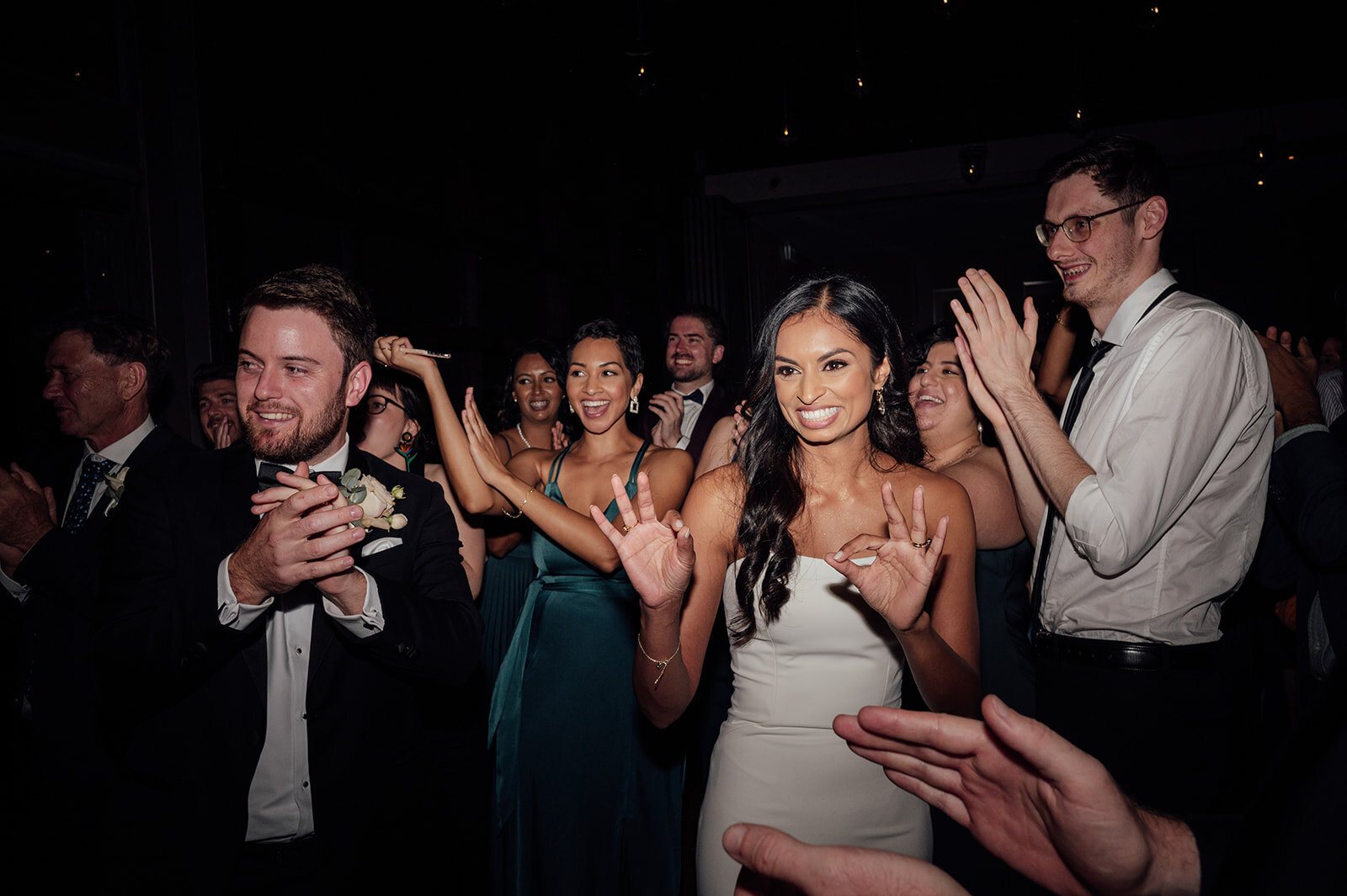 A bride dancing in the middle of her guests at night, everyone clapping