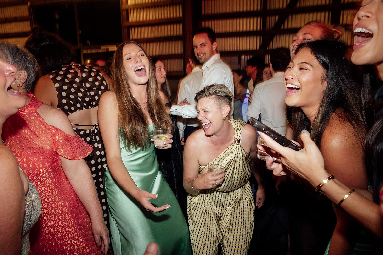 Friends in party dresses laughing together at a reception