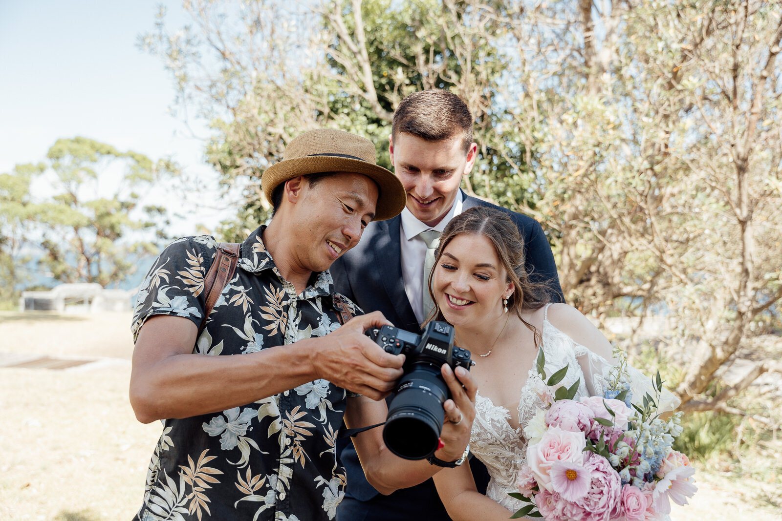 Kevin showing a laughing bride and groom a photo on the back of his camera